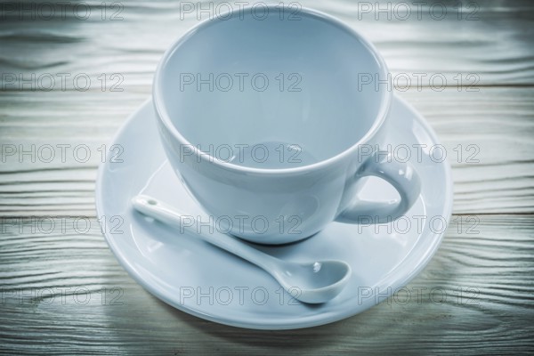 White ceramic cup saucer teaspoon on wooden board