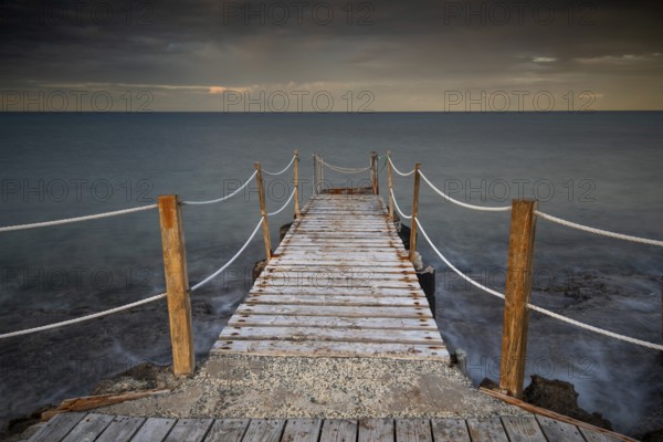 Long wooden pier in the sea at sunset. Protaras Cyprus