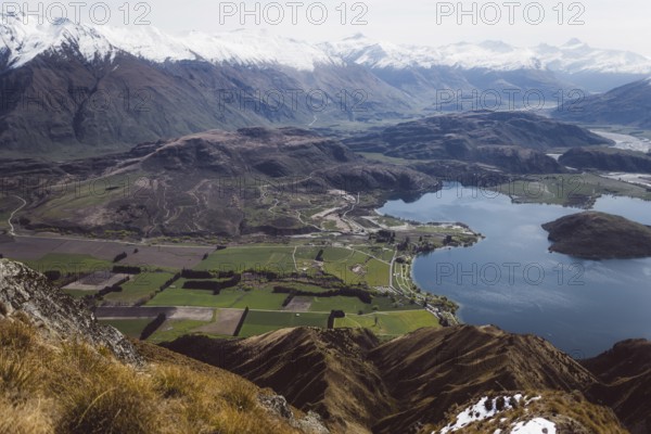 View of a wide valley with a lake, surrounded by fields and mountains, Roys Peak, Wanaka, New Zealand, Oceania