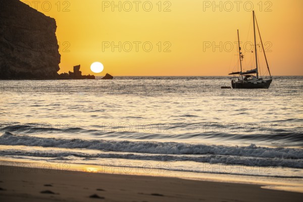 Sunrise during a storm, Calima. A haze-covered horizon turns orange as the sun rises as a ball. A boat is anchored in the sea. Landscape photograph in Gran Tarajal, Canary Islands, Spain, Europe