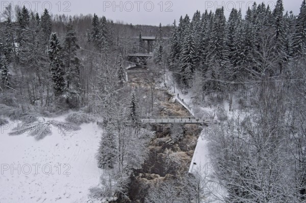 Aerial view of Myllykoski rapids on a cold winter day with snow covered ground and tree branches, Nurmijärvi, Finland, Europe