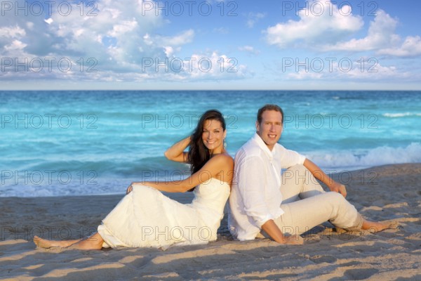 Couple in love sitting in blue beach on vacation travel