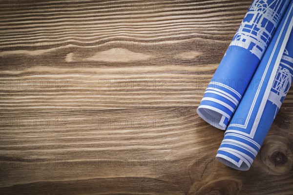 Blue rolled construction plans on wooden board copy space