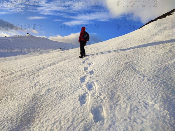 Person walking over snow-covered mountains, clear skies and footprints in the snow, Tromsø, Norway, Europe