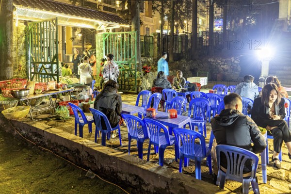 Empty blue chairs and tables under evening lights at a night market, restaurant in the streets of Sa Pa in Vietnam