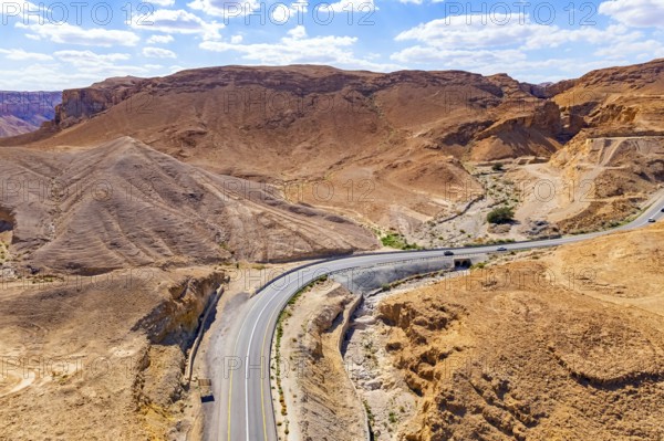 Asphalt highway meanders among the hills. Dead Sea mud has healing properties. Drone filming. Desert on the shores of the Dead Sea. Israel