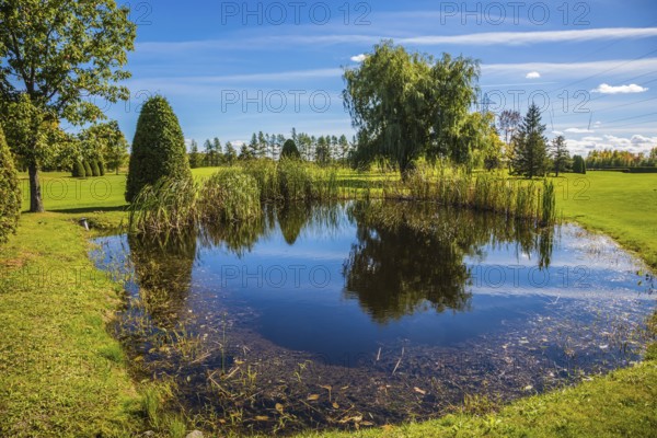 Adorable oval pond in the beautiful park. Red and orange autumn in French Canada. Concept of recreational tourism