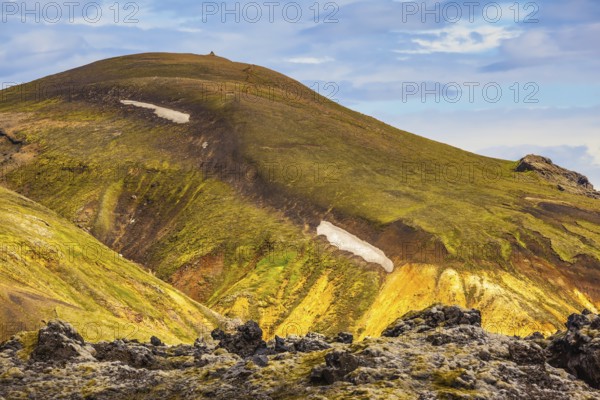 Incredible shades of rhyolitic mountains - yellow, orange, green and blue. Summer volcanic tundra. Travel to Iceland in July