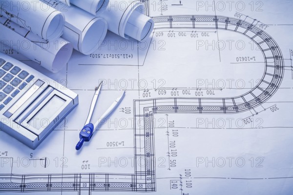 Stack of rolled blueprints calculator compass construction concept