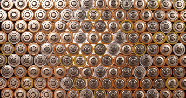 Multiple used AA alkaline batteries are seen arranged in a pile. Closeup front view from the plus side of the battery
