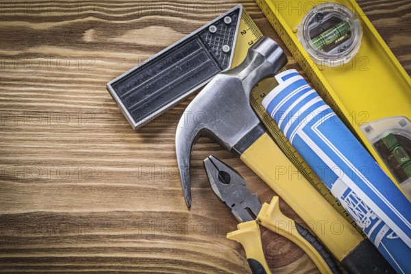 Blue blueprints construction level try square claw hammer pliers on wooden board