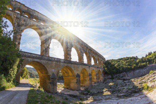 The bridge was built in Roman times on the river Gardon. Three-tiered aqueduct Pont du Gard - the highest in Europe. Provence, setting sun shines in sky