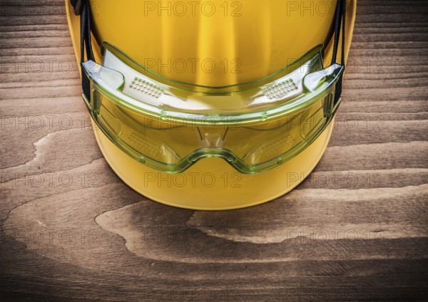 Safety spectacles and building helmet on wooden board construction concept