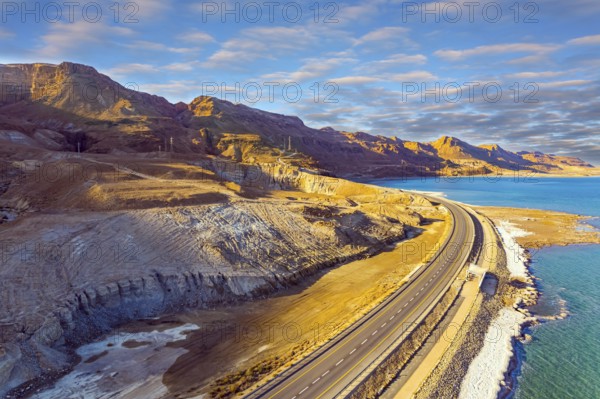 Shallowed Dead Sea photographed from a drone. Sunset. Evaporated salt was deposited along the shore. Asphalt highway runs along the seashore. The winter in Dead Sea