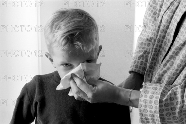 Boy in the 1950s. A mother holds a handkerchief over her sons nose as he blows his nose. Sweden 1956 Conard ref 3157