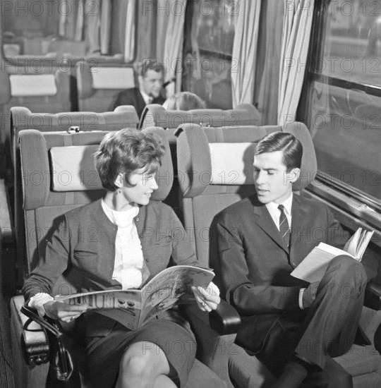 Train travel in the 1960s. A couple on a train, sitting comfortably in the carriage reading a magazine and a book. Sweden 1960s Kristoffersson ref DD118-11
