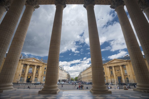 The grand columns of the Pantheon and neighboring Parisian buildings are uniquely seen from the inside looking out point of view in Paris, France, Europe