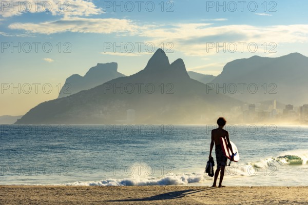 Young bodyboarder looking at the sea and Ipanema beach during a sunny afternoon