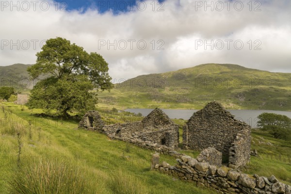 Grey clouds over Llyn Cwmystradllyn with a derelict ruin on the shore, near Penmorfa, Gwynedd, Wales, UK