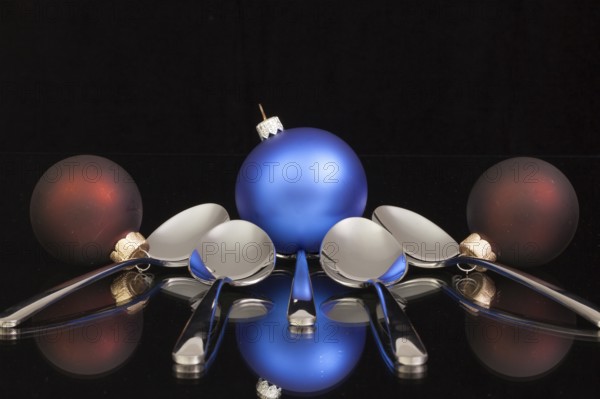 Blue Christmas decoration and five spoons on a black glass desk