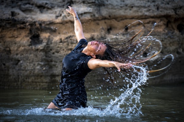 Middle-aged woman dancing and throwing water in the air, Maioris beach, llucmajor, Majorca, Balearic Islands, Spain, Europe