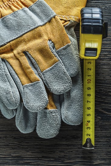 Set of tape measure protective gloves on wooden board