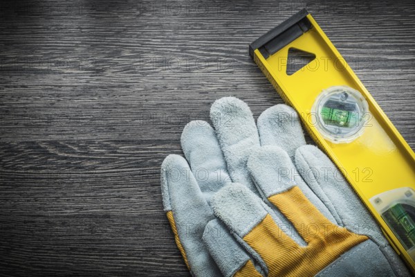 Yellow construction level protective gloves on wooden board