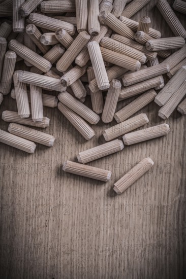 Variety of cylinder wooden dowel pins on wood board construction concept