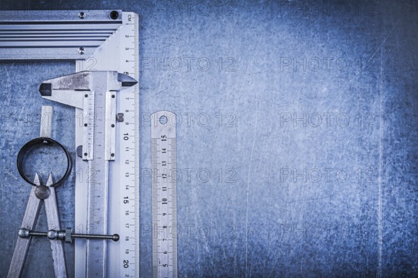Metal ruler try square slide caliper construction divider on metallic background