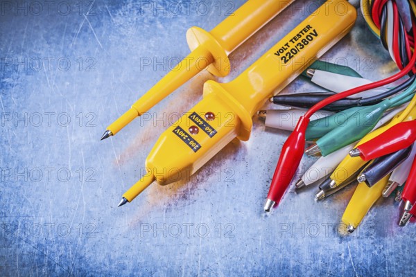 Yellow electrical tester set of multicolored crocodile clip cables on metallic background electricity concept