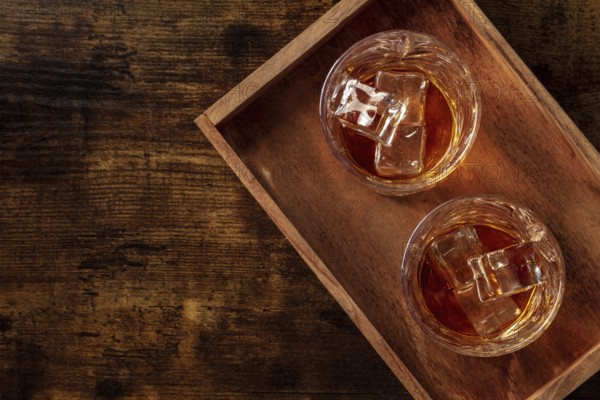 Whiskey in glasses with ice. Bourbon whisky on rocks on a dark rustic wooden background, overhead flat lay shot with copy space, Food photography, Food photography