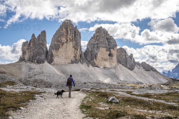 A female person hiking lonely with her dog around the Drei Zinnen mountains, the Dolomites in South Tirol