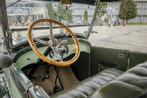 Lisbon, Portugal - Oct 15, 2023: Green interior with steering wheel and car dashboard of vintage Ford A Tudor Sedan. Wooden steering wheel and all-metal dashboard in selective focus