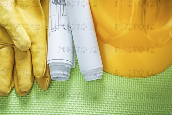 Protective leather gloves building helmet engineering drawings on green background construction concept