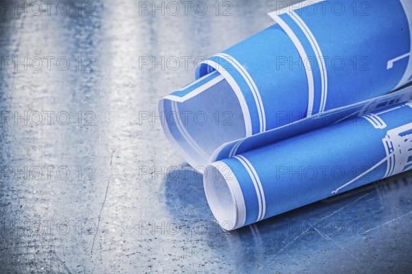 Blue rolled blueprints on scratched metallic background construction concept