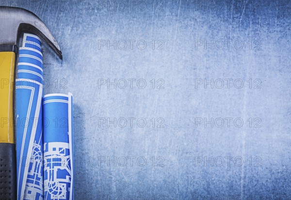 Blue rolled blueprints claw hammer on metallic background copyspace