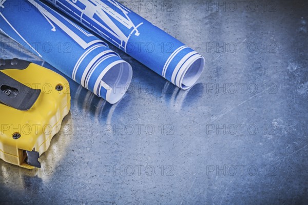 Blue construction drawings measuring tape on metallic background maintenance concept