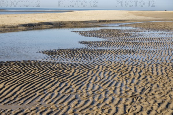 Water flowing over rippled sand forming beautiful patterns on a beach at low tide