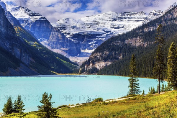Travel to the Rocky Mountains of Canada. The lake with azure water is surrounded by mountains and forests. Glacial Lake Louise. Sunny fine day. The concept of ecological, active and photo tourism