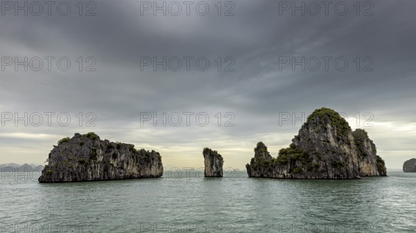 Rocky islands in the calm sea under a grey sky, The landscape and islands of Halong Bay in Vietnam