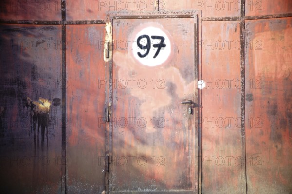 A rusty iron gate with a door and a painted sign