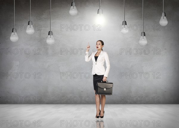 Business woman stands in a gray room with hanging bulbs