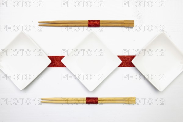Ceramic bowls and bamboo chopsticks for sushi food with red and white decoration