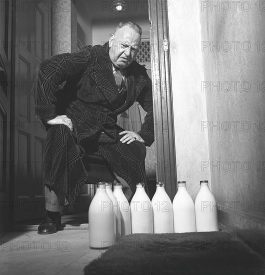 Man of the 1940s. A man visibly disapointed over the several milk bottles standing on his doorstep. He has stayed behind in the city apartment while his wife and family has a summer vacation. Perhaps he has enjoyed beer more than milk these bachelor days. Sweden 1942 ref C22-4