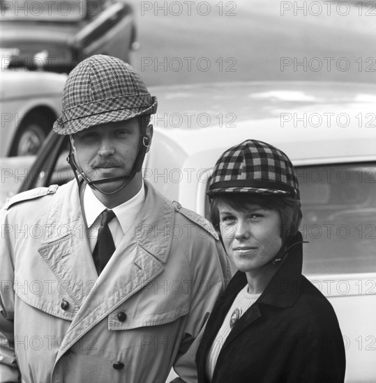 Driving in the 1960s. Car helmets was introduced in Sweden to encrease personal safety when driving cars. The manufacturers of the helmets hoped the sales of them would be boosted by the upcoming change from driving on the left side on the road, to the right. Oddly enough fewer accidents happened then prior the change. Pictured are a young couple wearing their helmets that were made differently for men and women. Sweden 1966 ref CV38-2