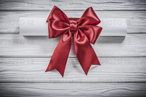 Paper scroll with red bow on wood board holidays concept