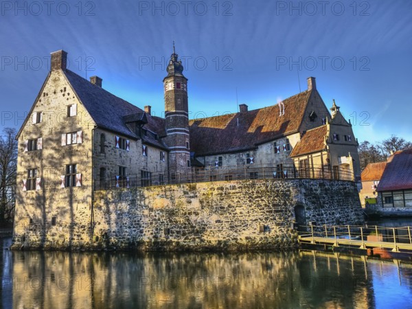 Medieval castle with a moat, shining in the sunlight against a blue sky, Lüdinghausen, münsterland, germany