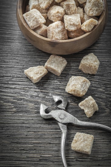Brown sugar cubes pliers bowl on vintage wood board