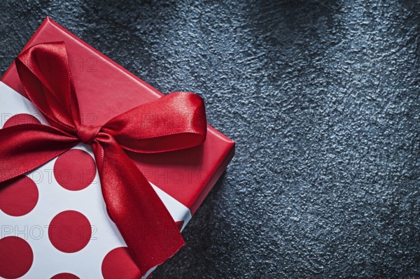 Wrapped gift box with tied bow on black background celebrations concept