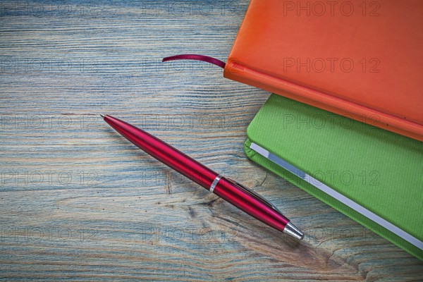 Set of closed notepads ballpoint pen on vintage wooden board office concept